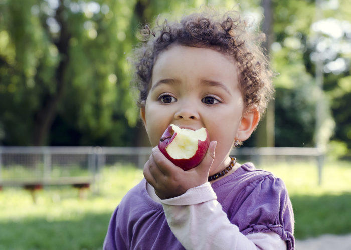 hunger-free-oklahoma_young-girl-eats-an-apple-outdoors