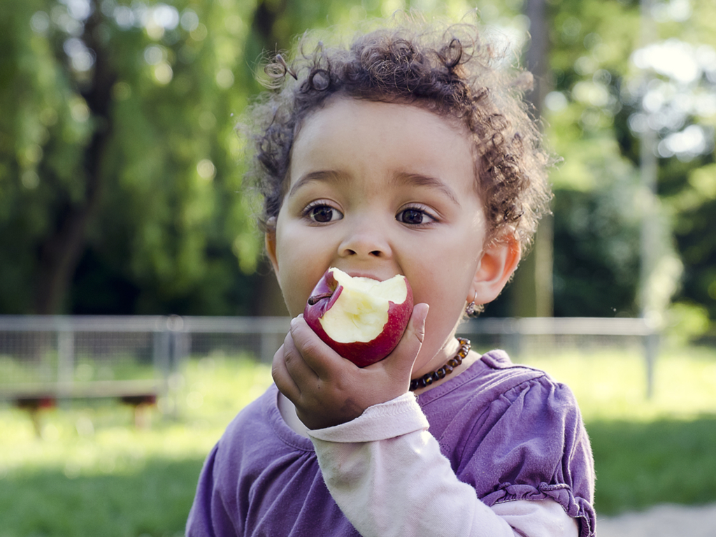 hunger-free-oklahoma_young-girl-eats-an-apple-outdoors_1024-x-786